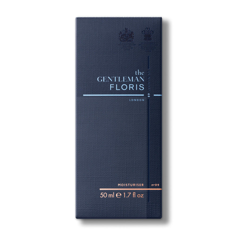 Die Floris London Feuchtigkeitscreme wird in einer dunkelblauen Verpackung präsentiert, die mit einem geprägten königlichen Wappen und stilvollen Designelementen in Silber und Orange verziert ist. Die Größe beträgt 50 ml.