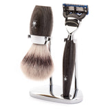 Hochqualitatives MÜHLE Rasierset aus Mooreichenholz, bestehend aus einem Rasierpinsel mit synthetischem Silvertip Fibre® und einem Rasierer für Gillette® Fusion™ Klingen, stylish auf einem verchromten Ständer präsentiert.